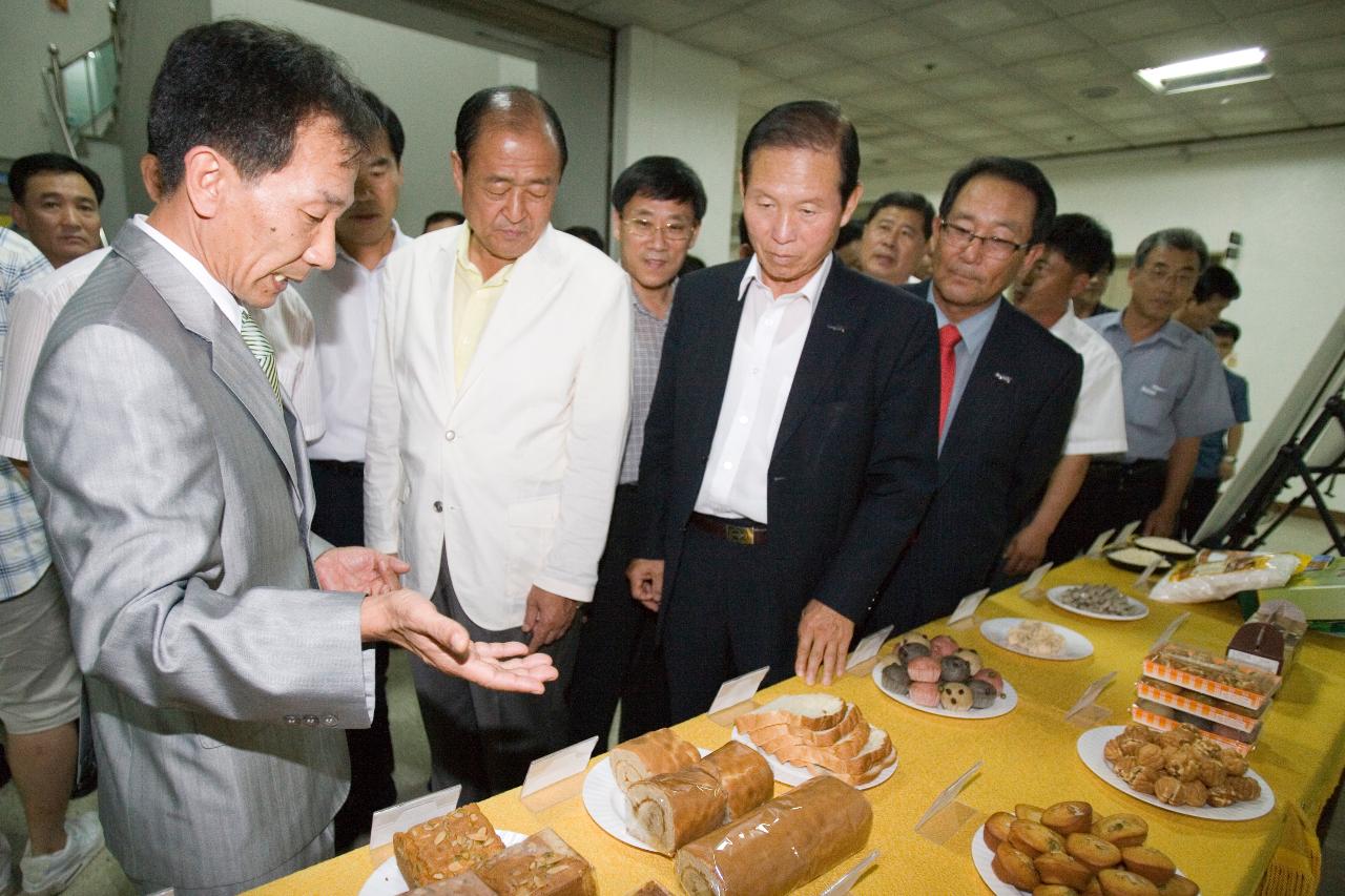 전시된 음식들을 가리키며 설명하고 있는 관계자와 듣고 있는 시장님과 관련인사들2