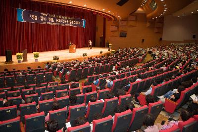 무대 위에서 말씀하고 계신 시장님과 객석에 앉아 듣고 계신 사람들