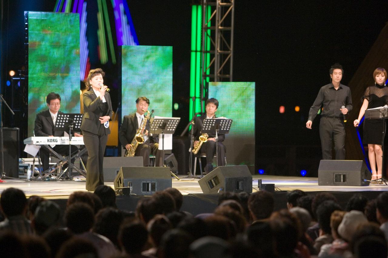 가요를 열창하고 있는 주부와 뒤에서 춤추고 있는 백댄서들과 환호하고 있는 시민들1