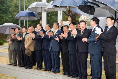 비가 오는 가운데 우산을 쓰고 농촌공사100주년을 축하하는 박수를 치고 있는 부시장님과 관련인사들