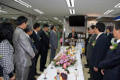 앞에서 말씀하고 계시는 대표님과 테이블 앞에 서서 듣고 계신 관련인사들