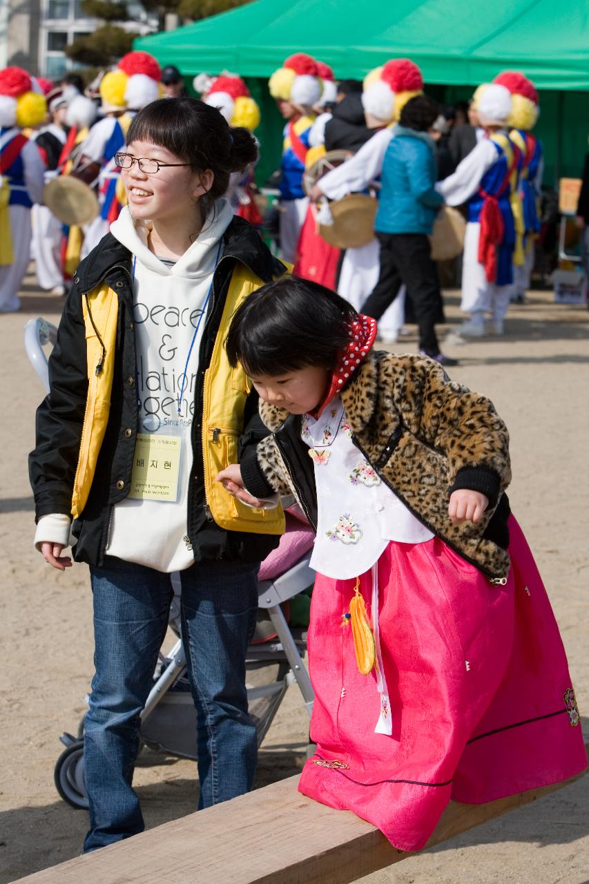 이쁜 한복을 입고 널뛰기에 조심스레 올라서는 아이