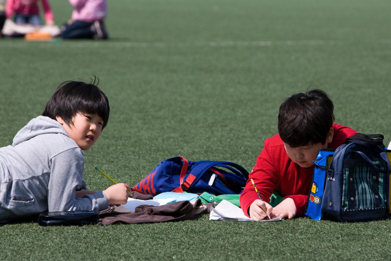 잔디밭에 앉아서 글을 쓰고있는 아이들2