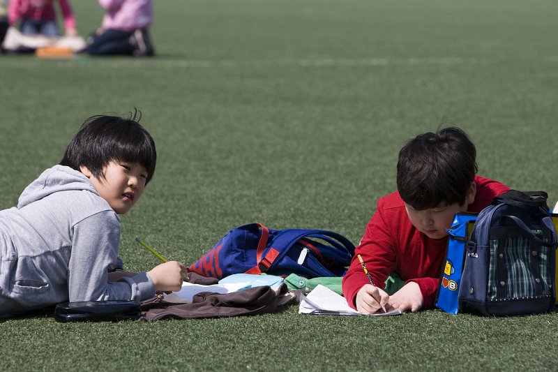 잔디밭에 앉아서 글을 쓰고있는 아이들2