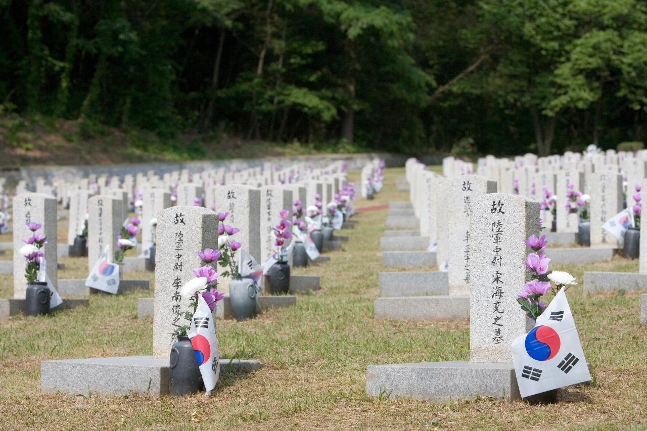 현충일 국립묘지에 묘비마다 무궁화와 국화꽃과 태극기가 꽂혀있는 모습