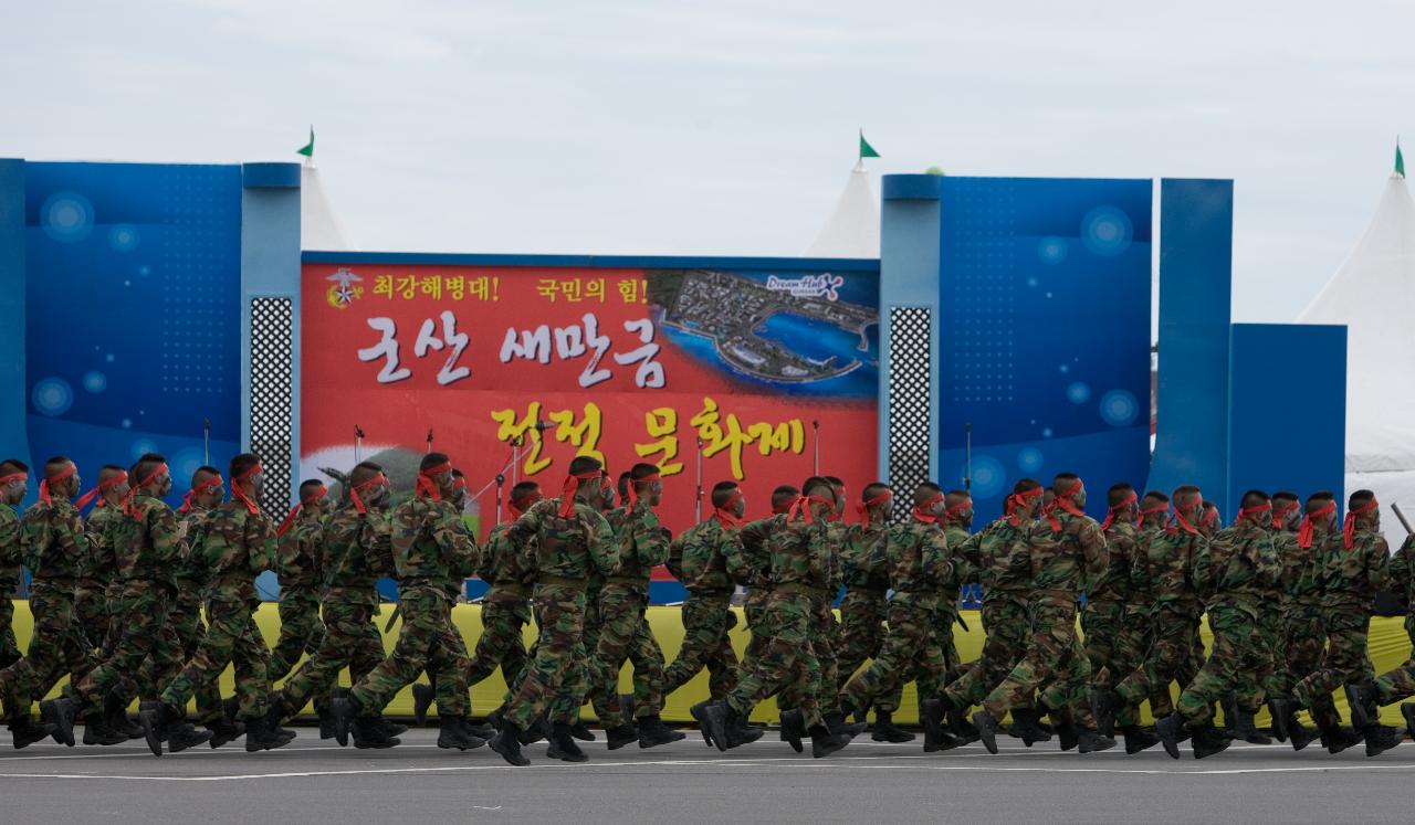 빨간 띠를 메고 해병대 전적문화재 무대앞을 행진하는 군인들