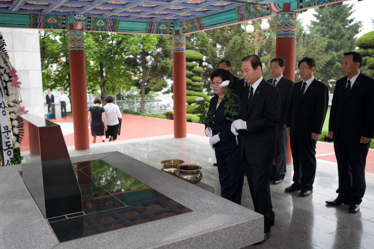 묘비에 국화꽃일 들고계신 시장님부부와 뒤에 일렬로 서있는 관계자들