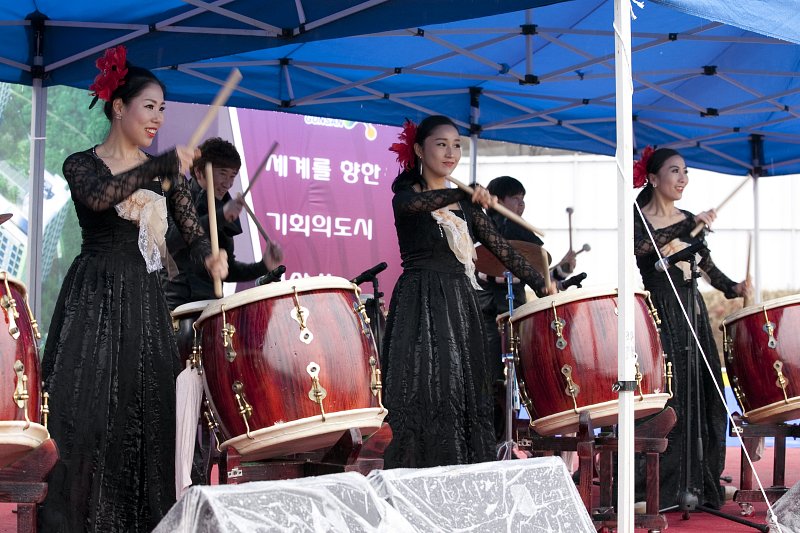 검은 드레스를 입은 공연단이 북을 치고있다.