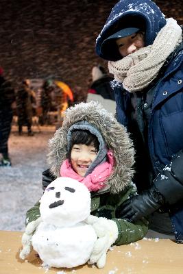 어린이가 눈사람을 만들고 웃고 있는 모습