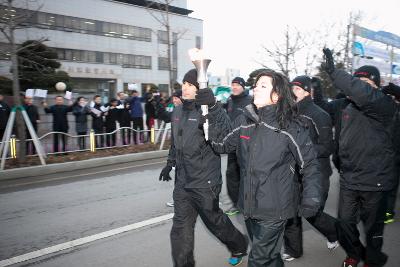 여성과 남성이 성화를 같이들고 도로위를 달리고있다.