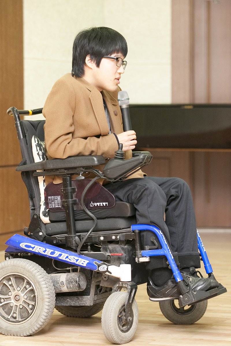 전동 휠체어를탄 장애우가 개강식 연설을 하고있다.